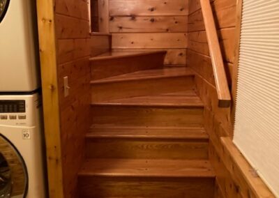 Wooden staircase in a home with natural wood paneling on the walls.